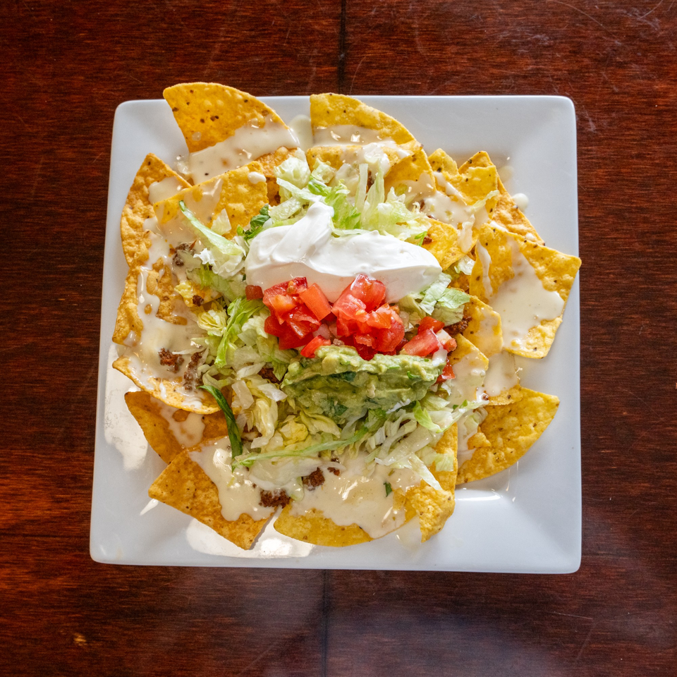 Tacos A La Diabla nachos with cheese, ground beef, lettuce, tomatoes, guacamole, and sour cream.