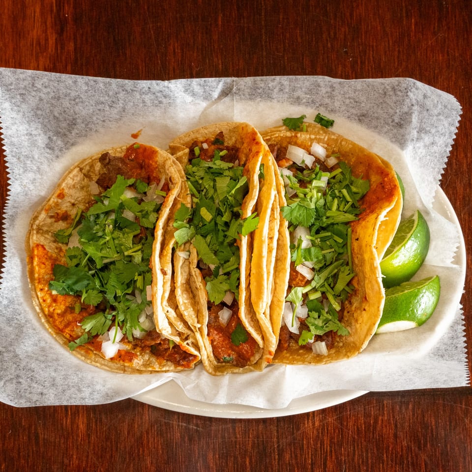 Three Tacos A La Diabla tacos with meat, cilantro, and onions, served with lime wedges.
