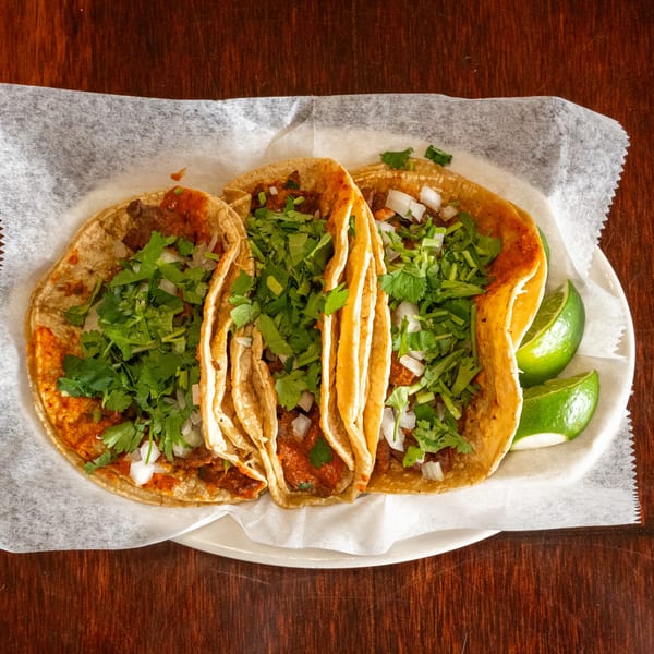 Three Tacos A La Diabla tacos with meat, cilantro, and onions, served with lime wedges.