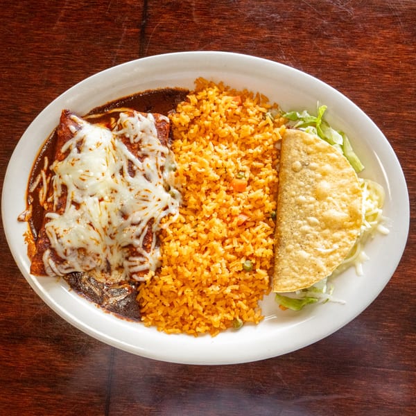 A white plate holds two enchiladas with melted cheese, a side of orange rice, and a crispy taco.
