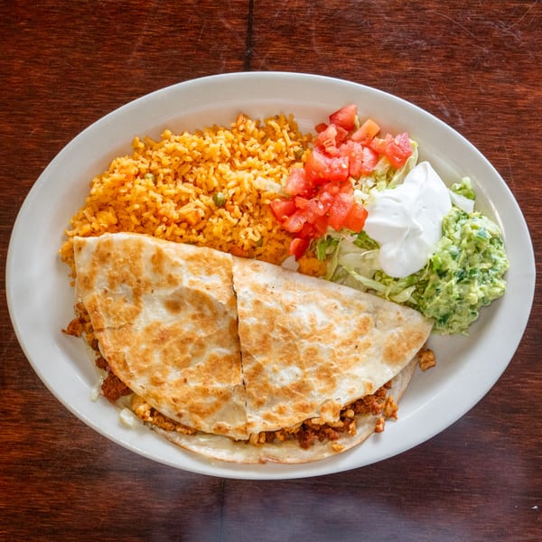 Tacos A La Diabla quesadilla meal with rice, guacamole, sour cream, lettuce, and tomatoes.