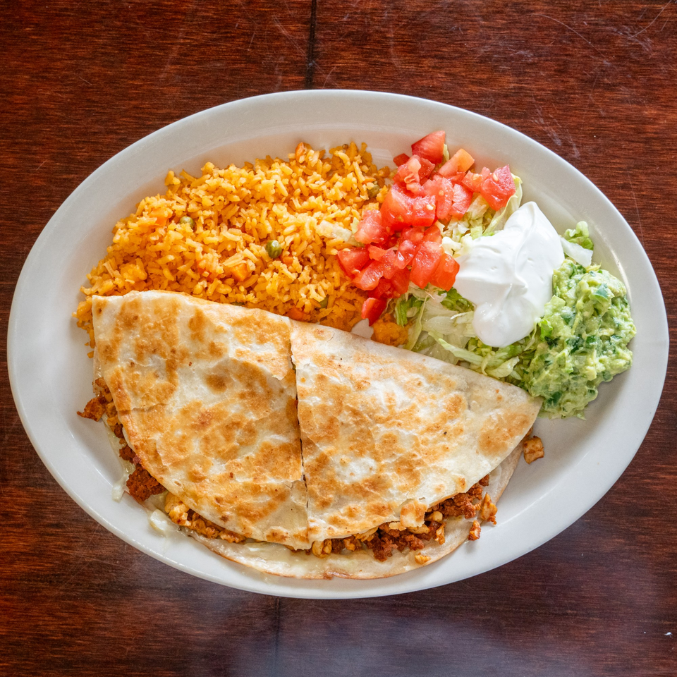 Tacos A La Diabla quesadilla meal with rice, guacamole, sour cream, lettuce, and tomatoes.