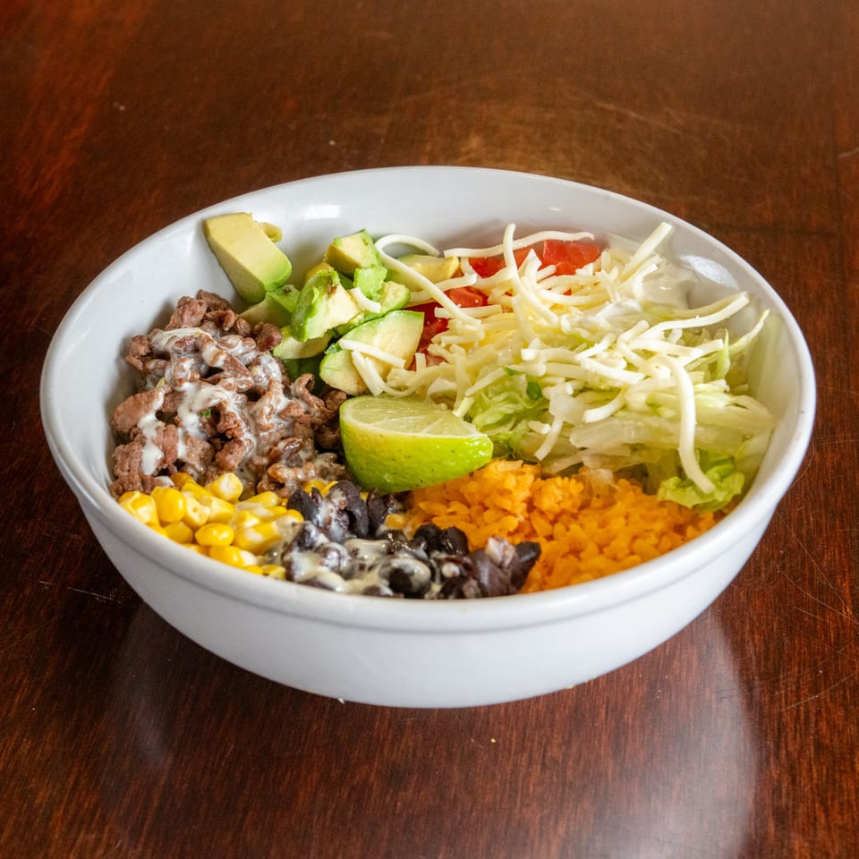 A Tacos A La Diabla Mexican bowl with steak, avocado, corn, black beans, rice, and cheese.