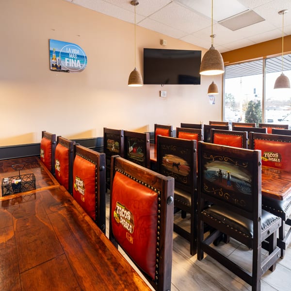 Interior of Tacos A La Diabla, featuring wooden tables, red leather chairs, and decorative wall art.