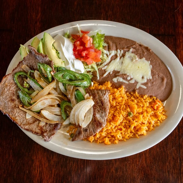 Carne asada with grilled onions and peppers, rice, refried beans, avocado, and sour cream.