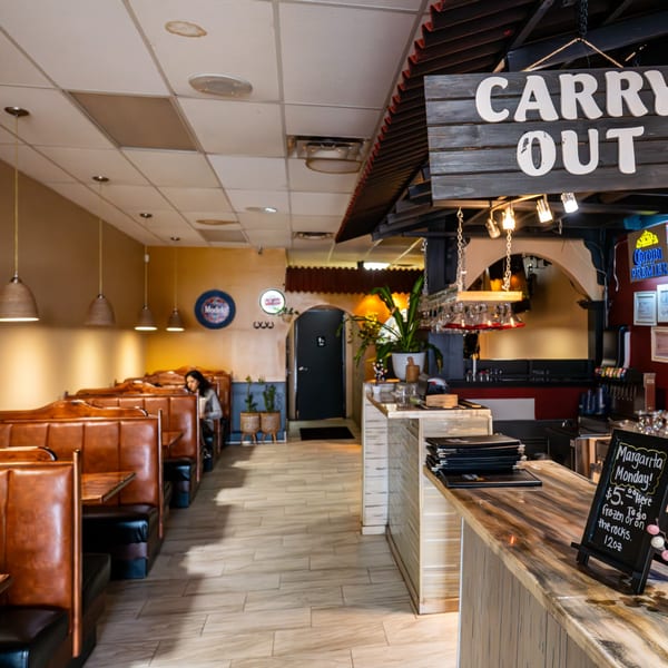 Interior of Tacos A La Diabla restaurant with booths, a bar, and a "Carry Out" sign.