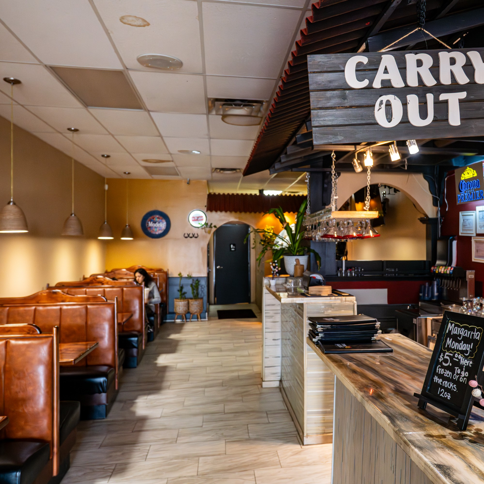 Interior of Tacos A La Diabla restaurant with booths, a bar, and a "Carry Out" sign.