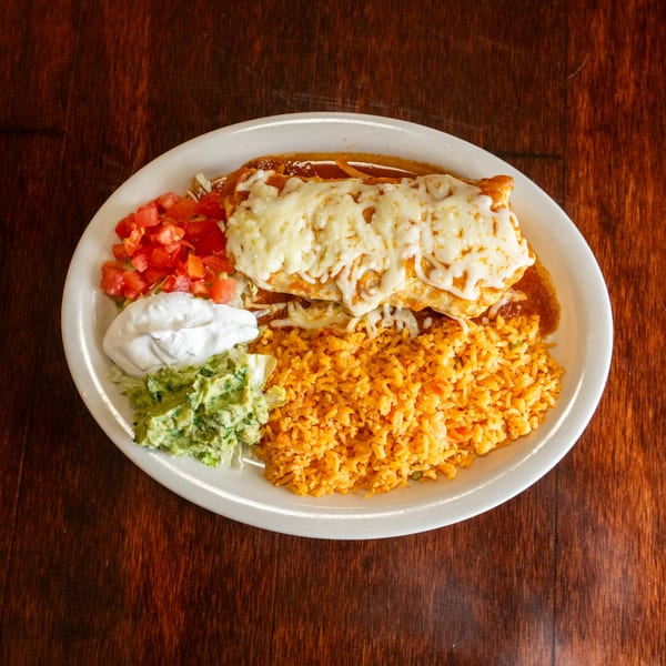 A Tacos A La Diabla burrito plate with rice, guacamole, sour cream, and diced tomatoes.